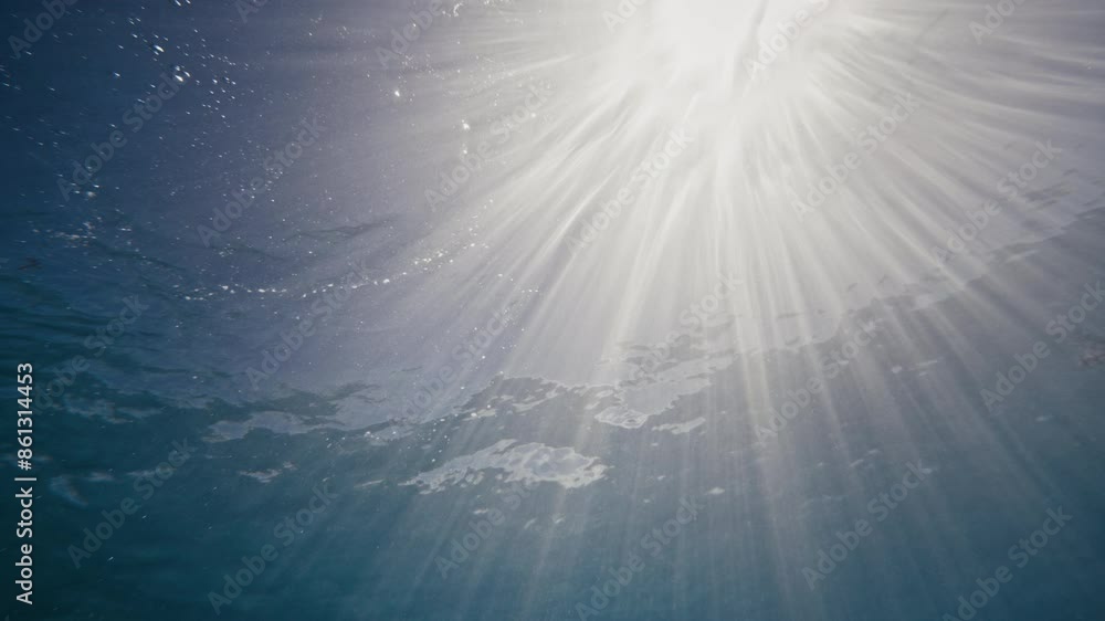 Aufkleber light rays sparkle and spread out in dazzling rows through ocean surface, underwater view in slow mo