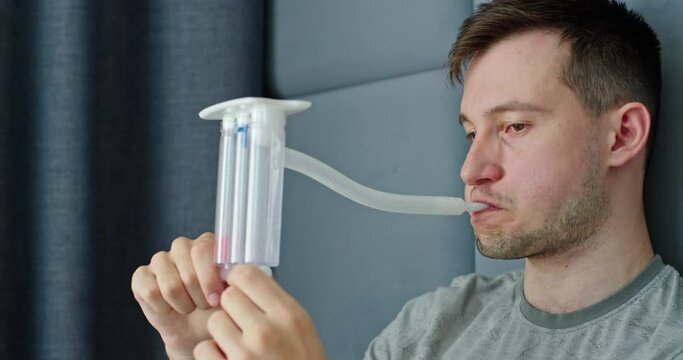 A young man tests his lungs using a spirometer.