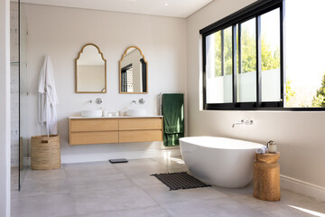 Modern bathroom with freestanding bathtub, double sink vanity, and large windows, copy space