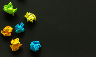 crumpled sheets of colored paper on a dark background, failed attempts, motivation concept