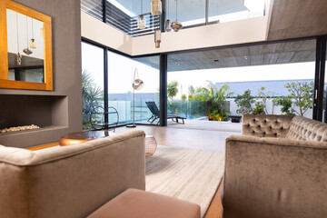 Modern living room with large windows, stylish furniture, and outdoor patio area