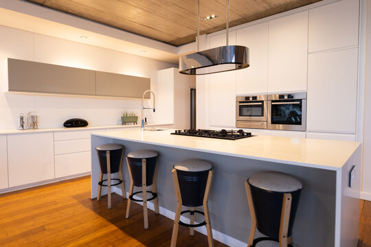 Modern kitchen with sleek white cabinets, island, and bar stools in home