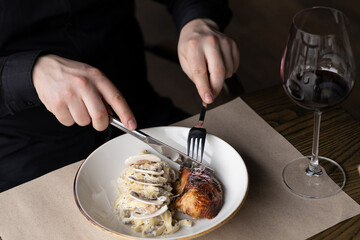 Male hands cutting roasted chicken or turkey and creamy pasta or mashed potatoes