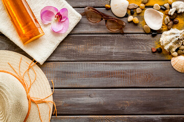 Shells and sea sand on wooden board with straw hat and sunglasses. Beach summer background