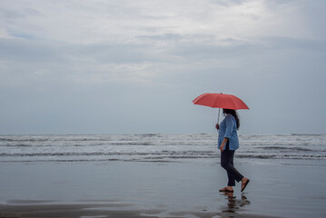 A Women with an umbrella on tropical beach on a cloudy and rainy day