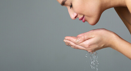 Beauty Concept. Beautiful Woman Washing Face with Water Over Grey Background, Side View