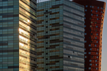 This striking image shows the sun's rays reflecting brightly off the modern skyscrapers, casting a warm glow over the urban landscape, prominently featuring a red cylindrical building in Barcelona Sp