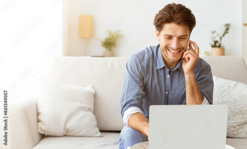 Poster A man smiles while sitting on a couch, using a laptop and talking on the phone. He appears to be relaxed and happy.