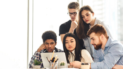 Remote education. A collaborative scene unfolds in the library where multiracial students use various devices to study. The environment is calm, with a focus on shared knowledge and technology.