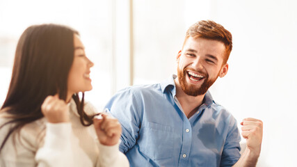 Happy man and woman are captured laughing heartily in a professional office setting. They are sharing a moment of joy and camaraderie, possibly during a break or after a successful meeting.