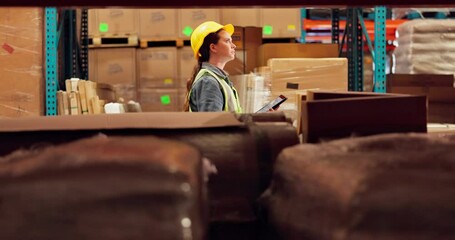 Logistics, woman and walking with tablet in warehouse in helmet for safety in supply chain or freight. Female person, industry and quality control in packaging, shipping or stock management of goods