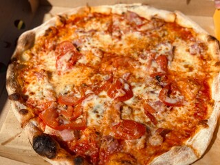 Outdoor lunch with a take away pizza in a cardboard. Close up of pizza at the park. 