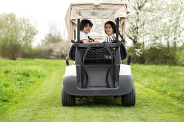 Fototapeta premium Young people driving a vehicle in a golf club and looking contented