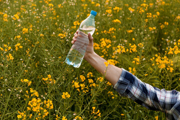 The guy holds a bottle of water in nature