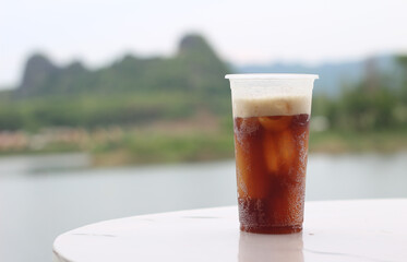 plastic cup of beer on table with mountain background