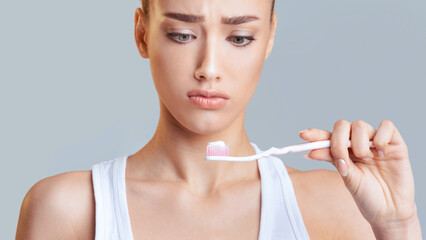 The image features a close-up portrait of a young woman holding a toothbrush with toothpaste on it....