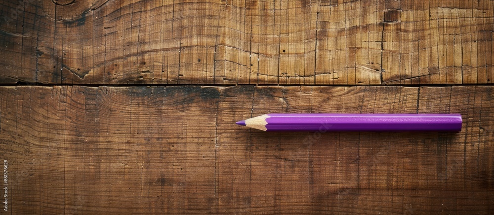 Poster An aerial shot of a purple pencil and paperclip on a wooden backdrop with space for an image. copy space available