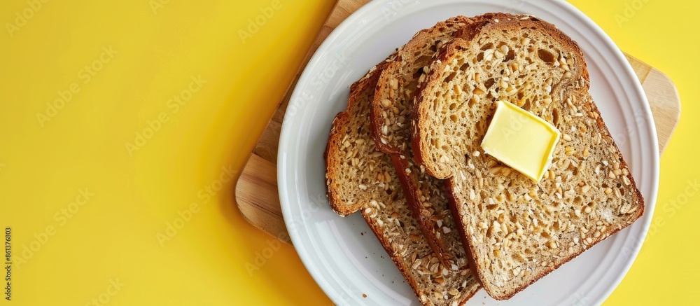 Poster top view of wholegrain bread on a cutting board with butter on a plate, set against a yellow backgro