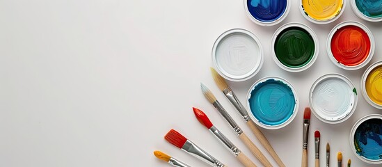 Paint cans arranged with brushes on a white backdrop, ideal for a copy space image.