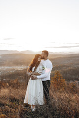 A couple is standing on a hillside, with the man kissing the woman's neck. The scene is serene and romantic, with the sun shining brightly in the background