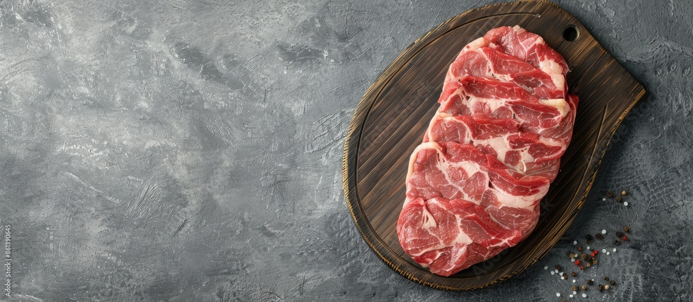Poster Top view image of marbled raw pork steak on a cutting board against a gray backdrop, with room for text or additional elements.