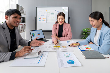A group of people are sitting around a table with a whiteboard behind them