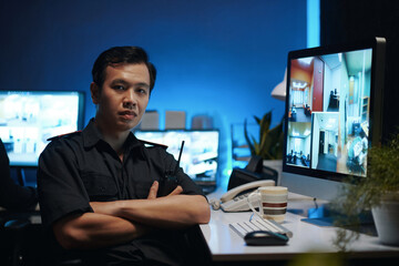 Portrait of young security worker with radio looking at camera while sitting in security room