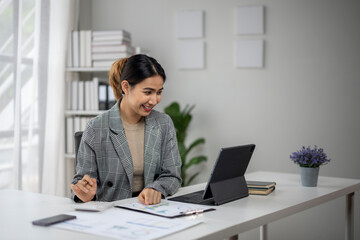 A woman is sitting at a desk with a laptop and a tablet