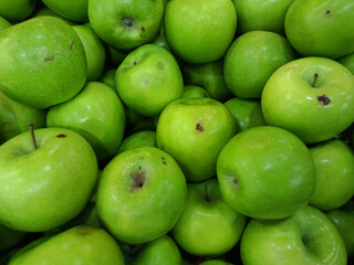 high-resolution image of a bunch of fresh, green apples closely packed together. The apples are glossy and vibrant, with smooth and slightly dimpled skins.