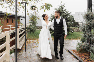 A bride and groom are walking down a path, the bride holding a bouquet. Scene is happy and celebratory