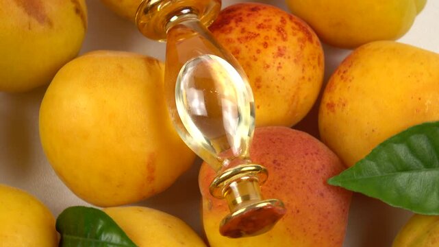 Glass bottle with apricot kernel oil placed on the ripe fresh apricot fruit, background