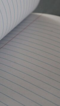 Primer plano de unas hojas de papel de un cuaderno escolar en movimiento. Video vertical.