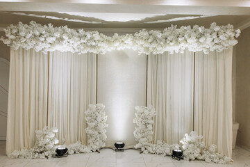 A white floral arrangement with a backdrop of white fabric
