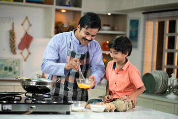 Happy Father And Son Beating Eggs In The Kitchen 