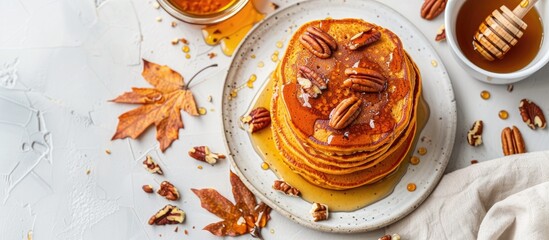 Autumn breakfast of pumpkin pancakes topped with pecans and honey on a white table, with space for additional images. Classic seasonal dish with a stack of flavorful pancakes.