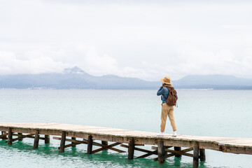 Woman with backpack walking on a jetty on turquoise water