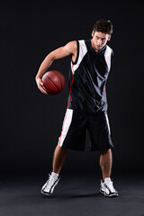 Fototapeta premium Fitness, basketball player and man in studio with practicing, workout or training for game. Activity, career and male athlete with sport equipment for match exercise isolated by black background.