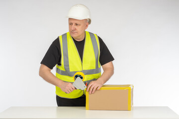 Man parcel packer. Guy seals cardboard box. Packer uses tape dispenser. Contractor prepares package...
