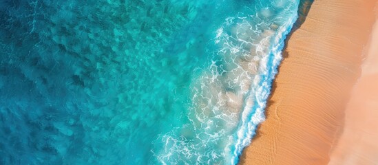Aerial view of a sandy beach with transparent blue and turquoise waters, suitable as a horizontal background with copy space image.