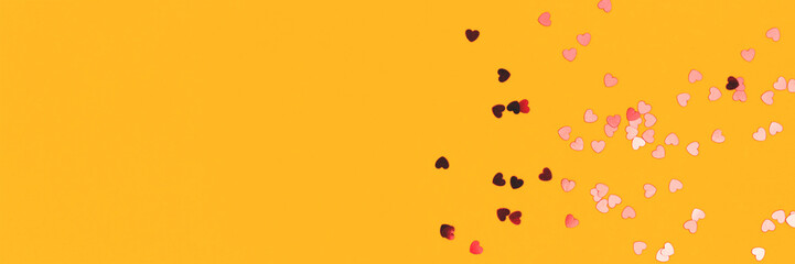 Banner with red confetti in a heart shape on a yellow background.