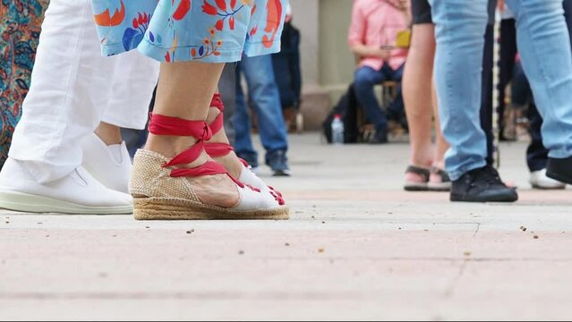 A group of sardanistas dancing sardanas, a typical regional Catalan dance, with a close-up of their traditional shoes called espardenyas. Sardanistes with espardenyes 