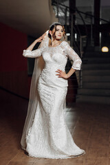 A woman in a white wedding dress poses for a picture. She is wearing a veil and a tiara