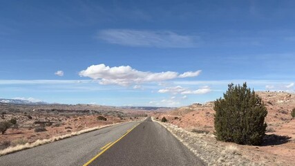 Point of View POV driving shot along the empty Burr Trail road, a scenic byway in Capitol Reef National Park, Utah. The road winds through a stunning, barren desert landscape of red rock - USA