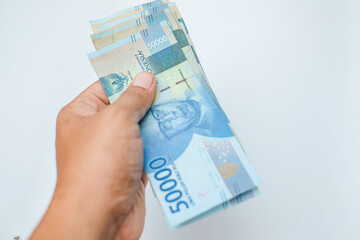 Male hand showing Indonesian rupiah banknotes.