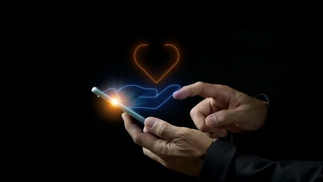 Healthcare, love, organ donation, mindfulness, wellbeing, insurance and praying concept. Businessman hand holding smartphone to show glowing neon line of hand holding heart icon on virtual screen.