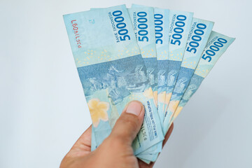 Male hand showing Indonesian rupiah banknotes.