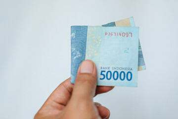 Male hand showing Indonesian rupiah banknotes.