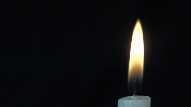 クローズアップされた白いろうそくの火が点火する瞬間から吹き消えるまで