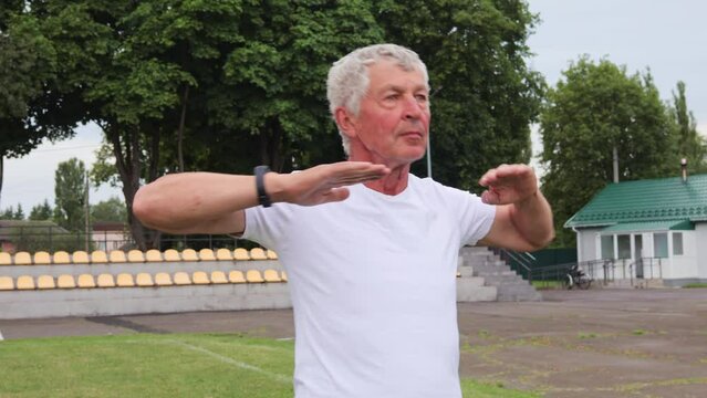 Senior man engaging in fitness workout at the stadium to maintain healthy and active lifestyle through regular exercise and training warming up arms before training