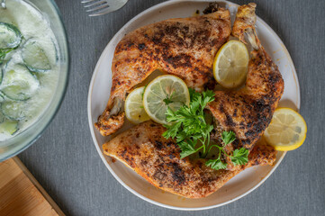 Roasted chicken legs on a plate with lemon and parley garnish. Served ready to eat on a table